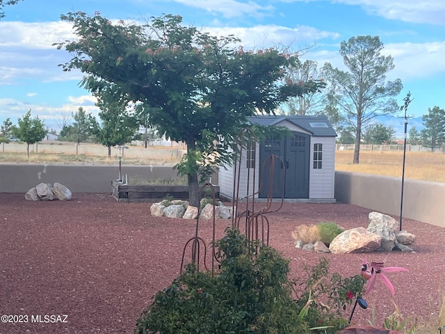 view of yard featuring fence, a vegetable garden, an outdoor structure, and a shed