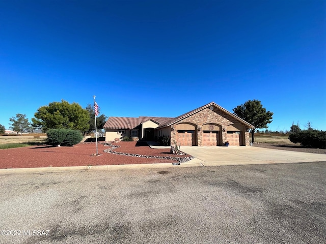 view of front facade featuring a tiled roof, concrete driveway, stucco siding, a garage, and stone siding