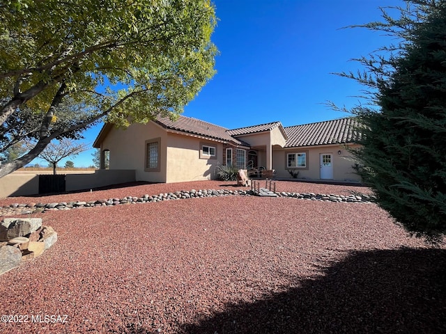 view of front of house with stucco siding, fence, and a tile roof