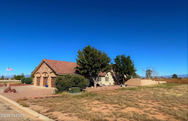 view of front of house featuring stone siding, driveway, and a tiled roof