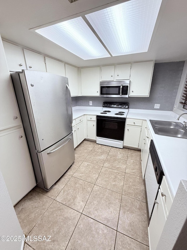 kitchen featuring light tile patterned flooring, a sink, light countertops, appliances with stainless steel finishes, and white cabinetry