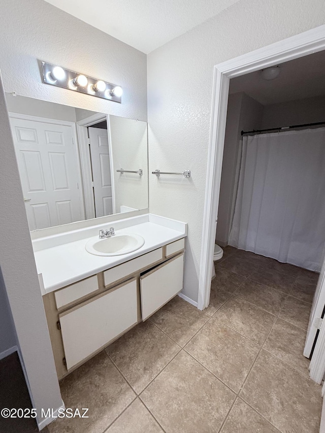 full bathroom featuring tile patterned flooring, toilet, a shower with curtain, a textured wall, and vanity