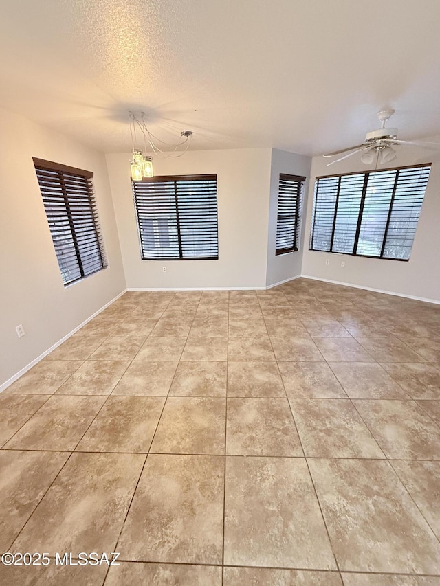 spare room featuring light tile patterned flooring, a ceiling fan, and a wealth of natural light