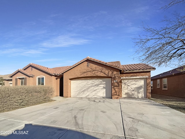 mediterranean / spanish-style house with a garage, concrete driveway, stucco siding, and a tile roof