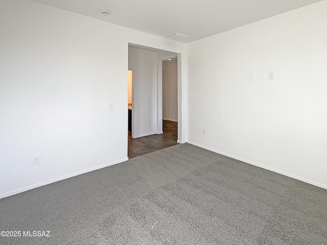 spare room with baseboards and dark carpet