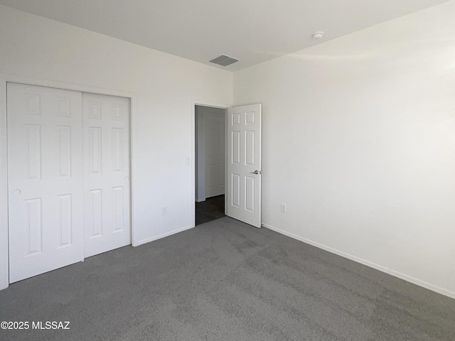 unfurnished bedroom featuring visible vents, baseboards, a closet, and dark carpet