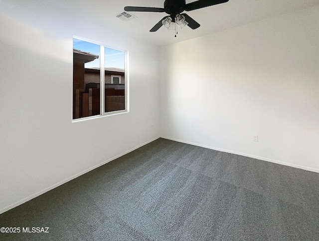 unfurnished room with a ceiling fan, visible vents, dark carpet, and baseboards