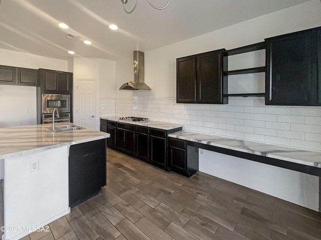 kitchen featuring tasteful backsplash, visible vents, stainless steel appliances, wall chimney exhaust hood, and a sink