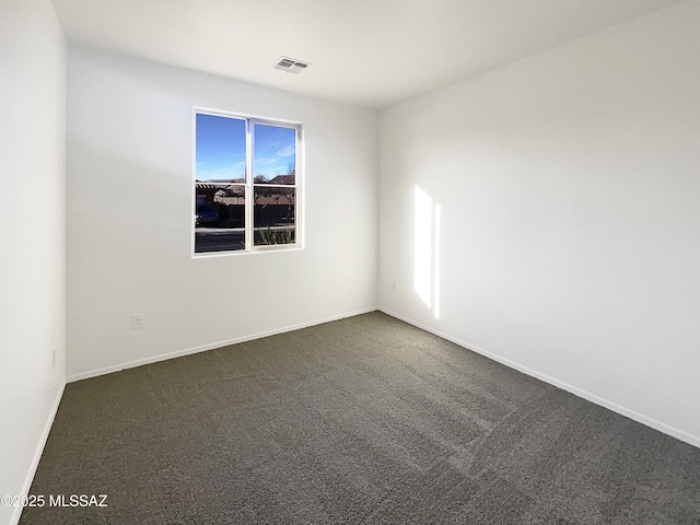 spare room with baseboards, visible vents, and dark carpet