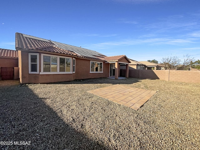 back of property with solar panels, a patio, a fenced backyard, and stucco siding