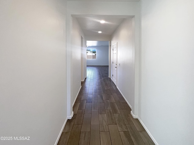 corridor featuring baseboards and wood finish floors