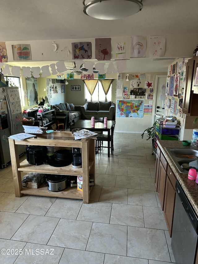 kitchen featuring light tile patterned floors, a sink, and stainless steel dishwasher