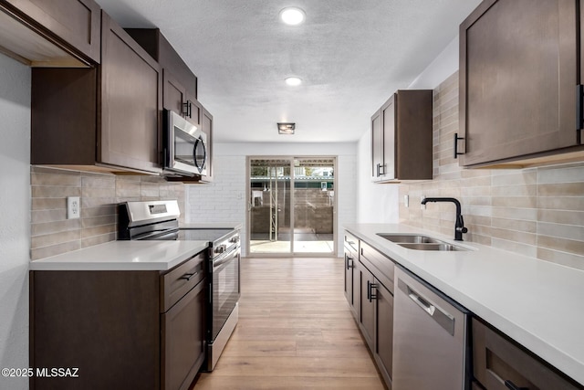 kitchen with a sink, light countertops, light wood finished floors, and stainless steel appliances