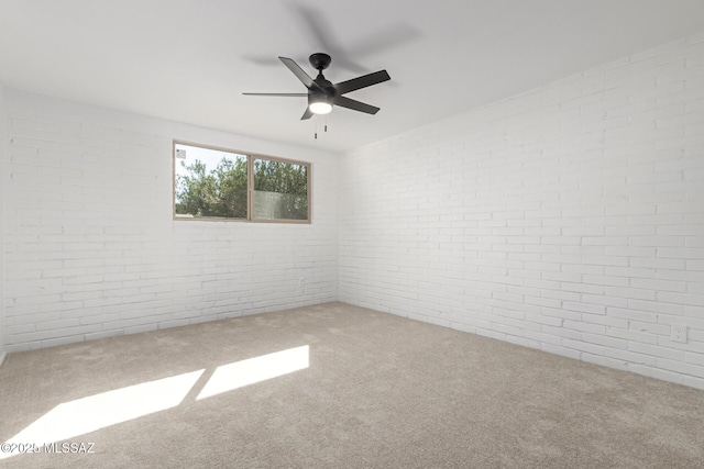 unfurnished room with carpet, brick wall, and a ceiling fan