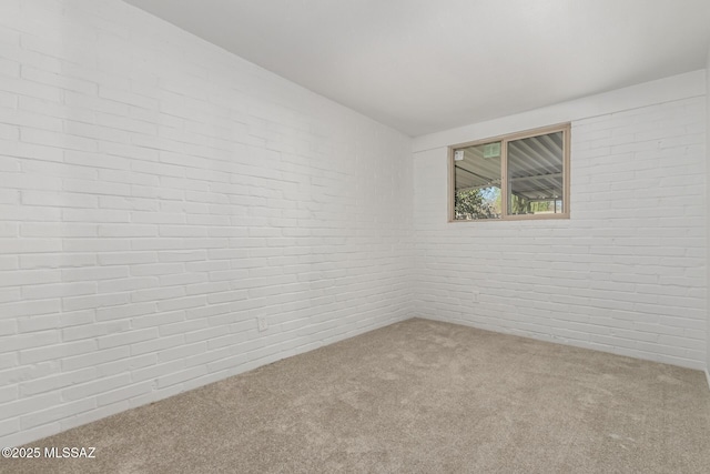 spare room with brick wall and carpet floors