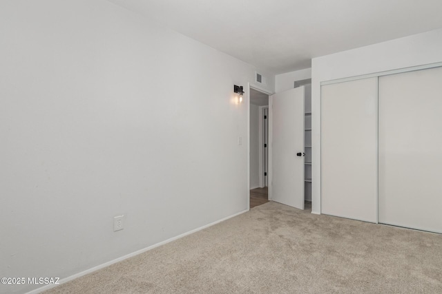 unfurnished bedroom featuring baseboards, a closet, carpet floors, and visible vents