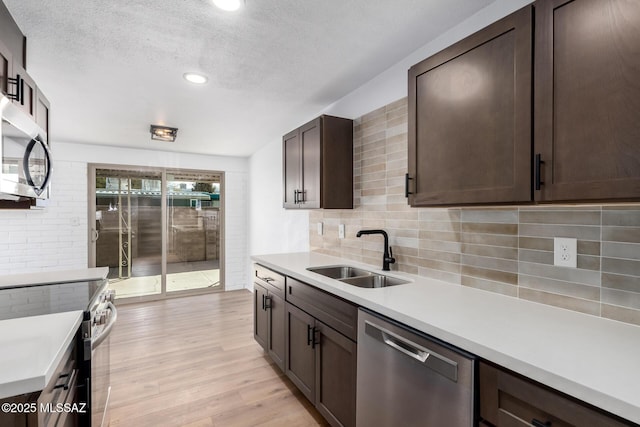 kitchen featuring light wood finished floors, appliances with stainless steel finishes, light countertops, and a sink