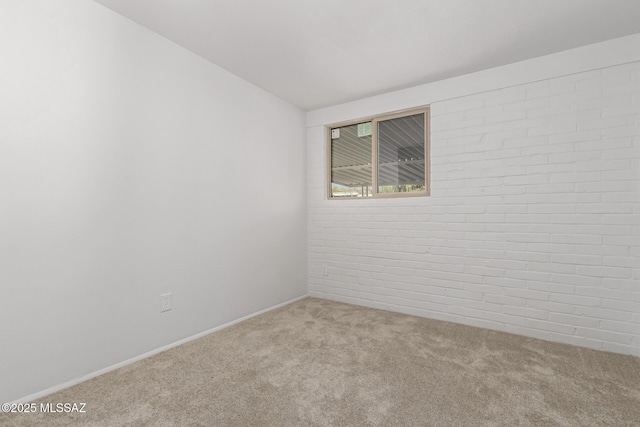 carpeted spare room with brick wall