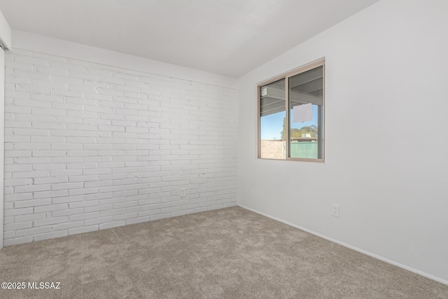 spare room with carpet and brick wall