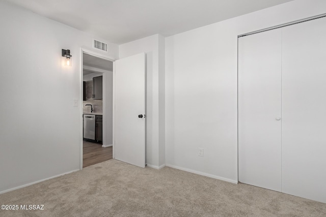 unfurnished bedroom with a sink, visible vents, a closet, and carpet flooring