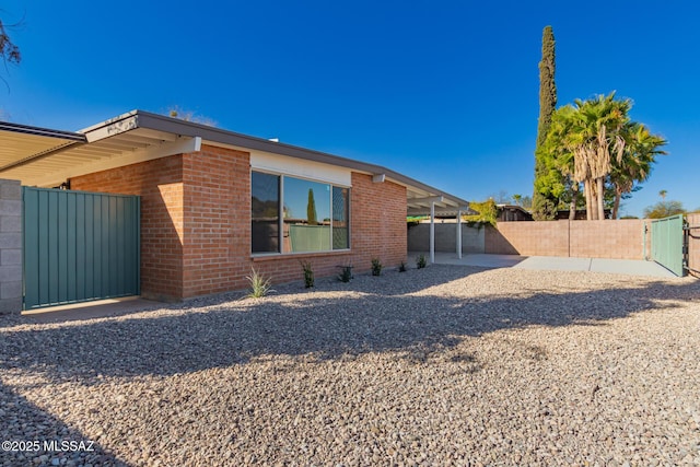 exterior space featuring brick siding, a gate, and fence