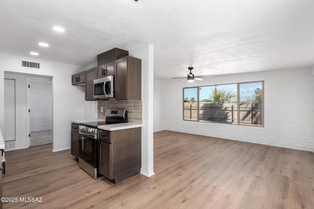 kitchen featuring light wood-type flooring, visible vents, dark brown cabinetry, and appliances with stainless steel finishes