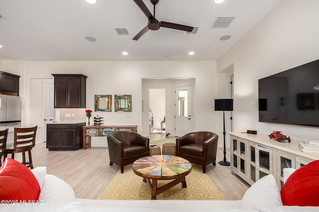 living room featuring ceiling fan, visible vents, recessed lighting, and light wood finished floors
