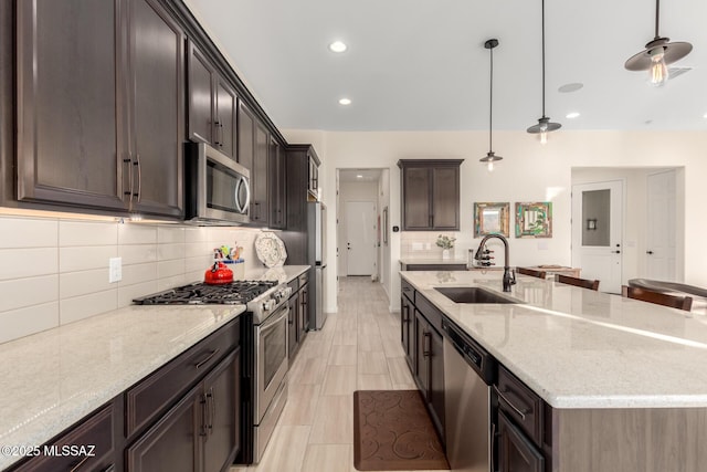 kitchen featuring light stone countertops, a sink, stainless steel appliances, and a spacious island