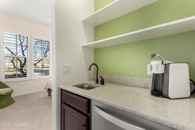 kitchen featuring light countertops, light colored carpet, stainless steel dishwasher, a sink, and dark brown cabinets