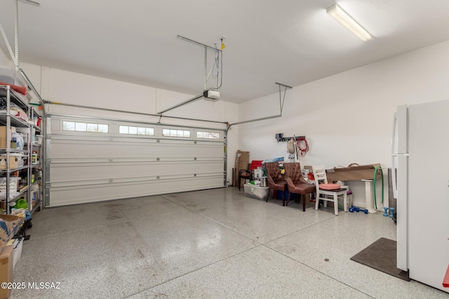 garage featuring freestanding refrigerator and a garage door opener