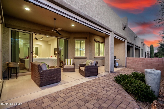 patio terrace at dusk featuring fence and a ceiling fan