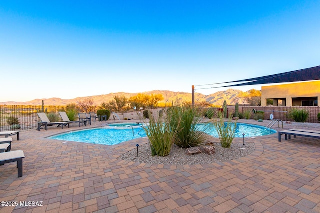 community pool with a mountain view, fence, and a patio area
