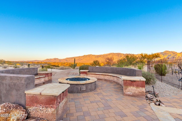 view of patio / terrace with a fire pit, fence, and a mountain view