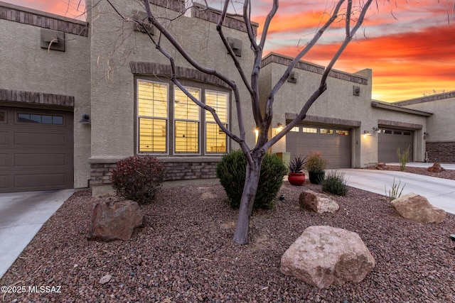 view of front of property with stone siding, concrete driveway, stucco siding, and an attached garage