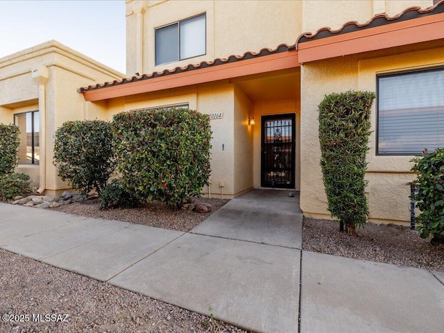 property entrance featuring stucco siding and a tiled roof