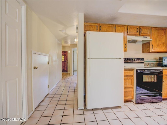 kitchen with light tile patterned floors, freestanding refrigerator, light countertops, under cabinet range hood, and range with electric stovetop