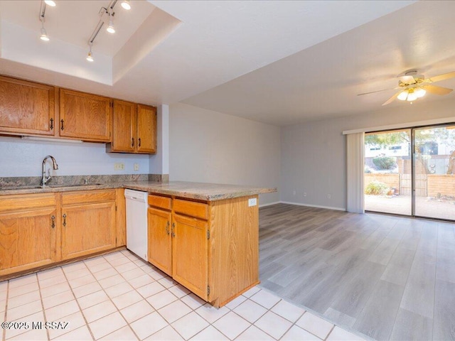 kitchen with light wood finished floors, a peninsula, a sink, white dishwasher, and track lighting