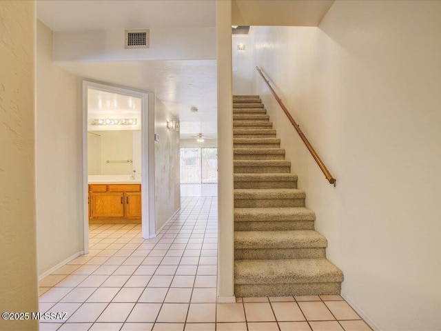 staircase with tile patterned floors, visible vents, and ceiling fan