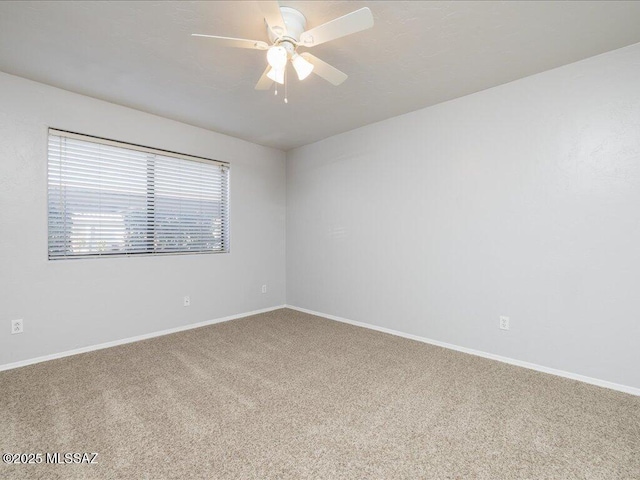 carpeted empty room featuring a ceiling fan and baseboards