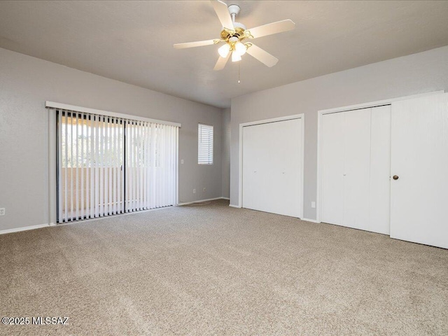 unfurnished bedroom with carpet, multiple closets, and ceiling fan