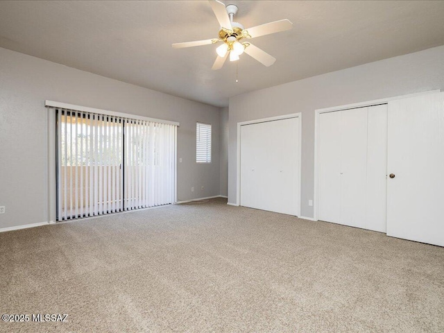 unfurnished bedroom with two closets, ceiling fan, baseboards, and carpet