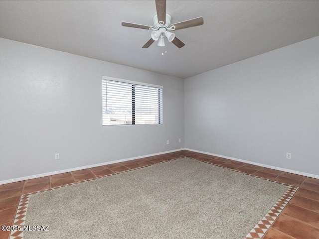 carpeted spare room with tile patterned flooring, baseboards, and ceiling fan