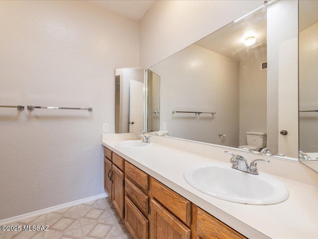 full bath with visible vents, a sink, double vanity, and toilet