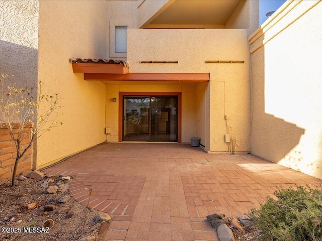 view of exterior entry featuring a patio and stucco siding