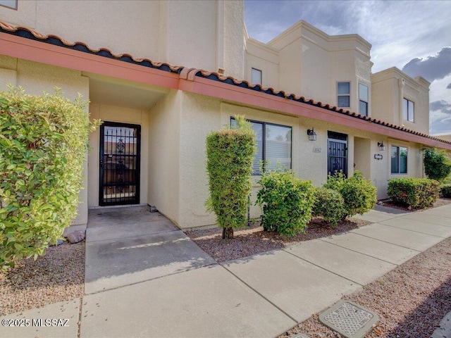 exterior space with a tiled roof and stucco siding