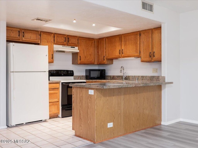 kitchen with black microwave, electric range oven, under cabinet range hood, visible vents, and freestanding refrigerator