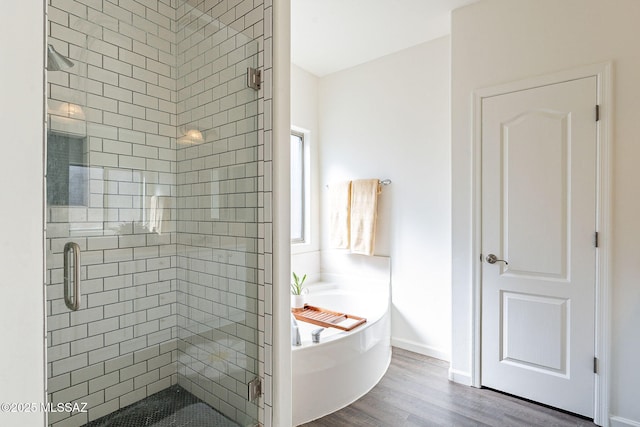 full bathroom with wood finished floors, a garden tub, and a stall shower