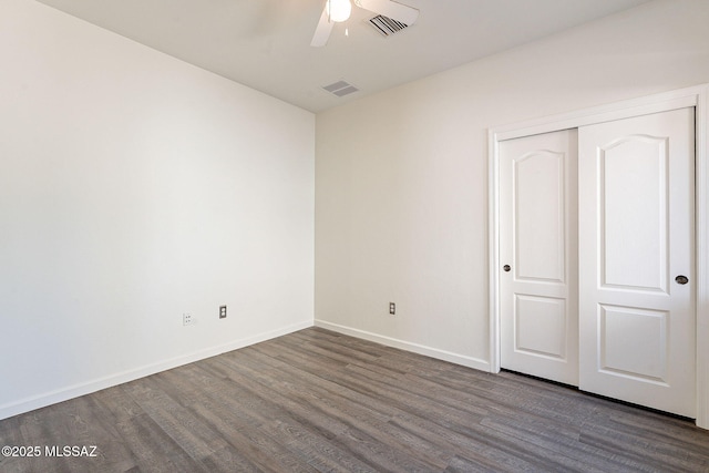 unfurnished bedroom with visible vents, dark wood-style floors, baseboards, and a closet