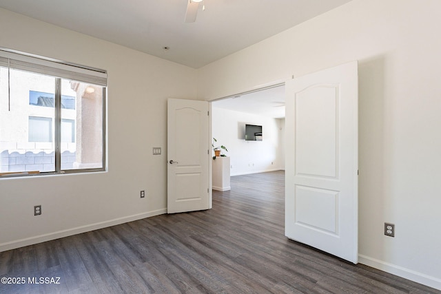 empty room with dark wood-type flooring, a ceiling fan, and baseboards