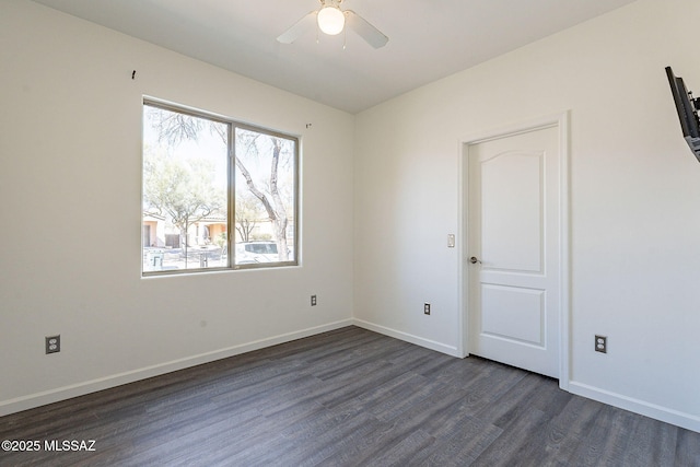 spare room with dark wood-type flooring, a ceiling fan, and baseboards